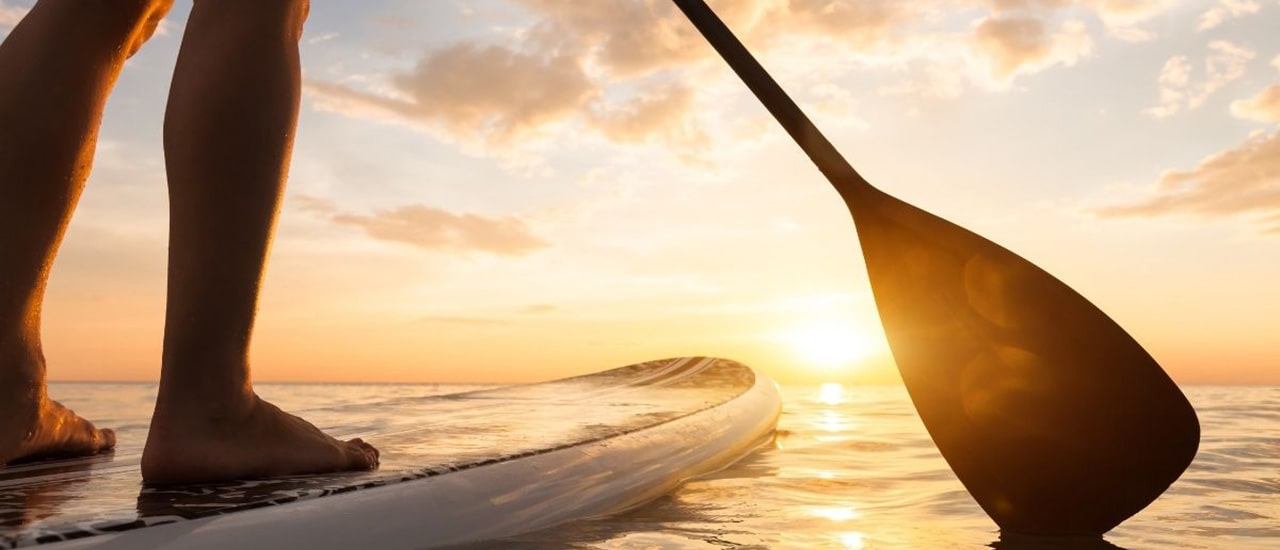 woman on paddleboard with sunset over longboat key