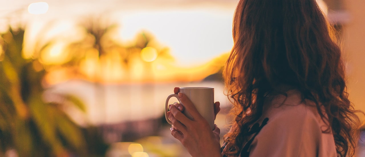 woman holding coffee looking out to longboat key sunset